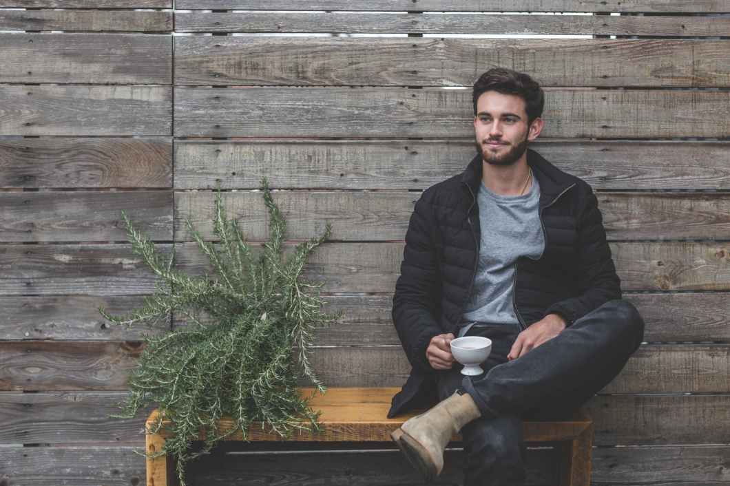 man sitting on bench having a cup of coffee