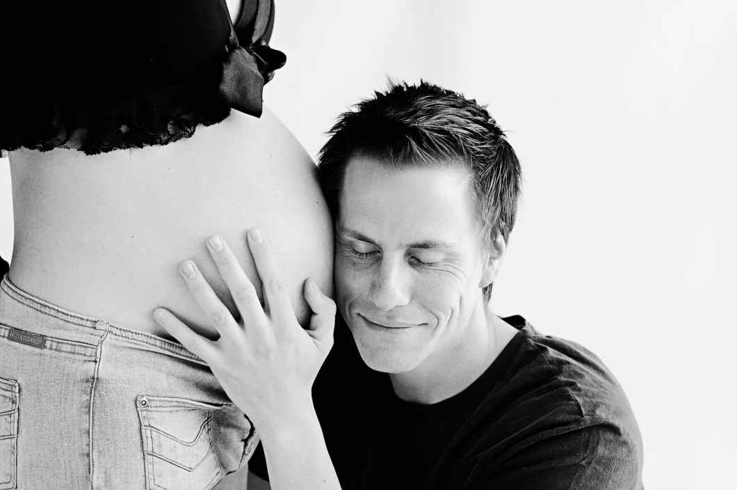 man wearing black listening on pregnant woman s stomach