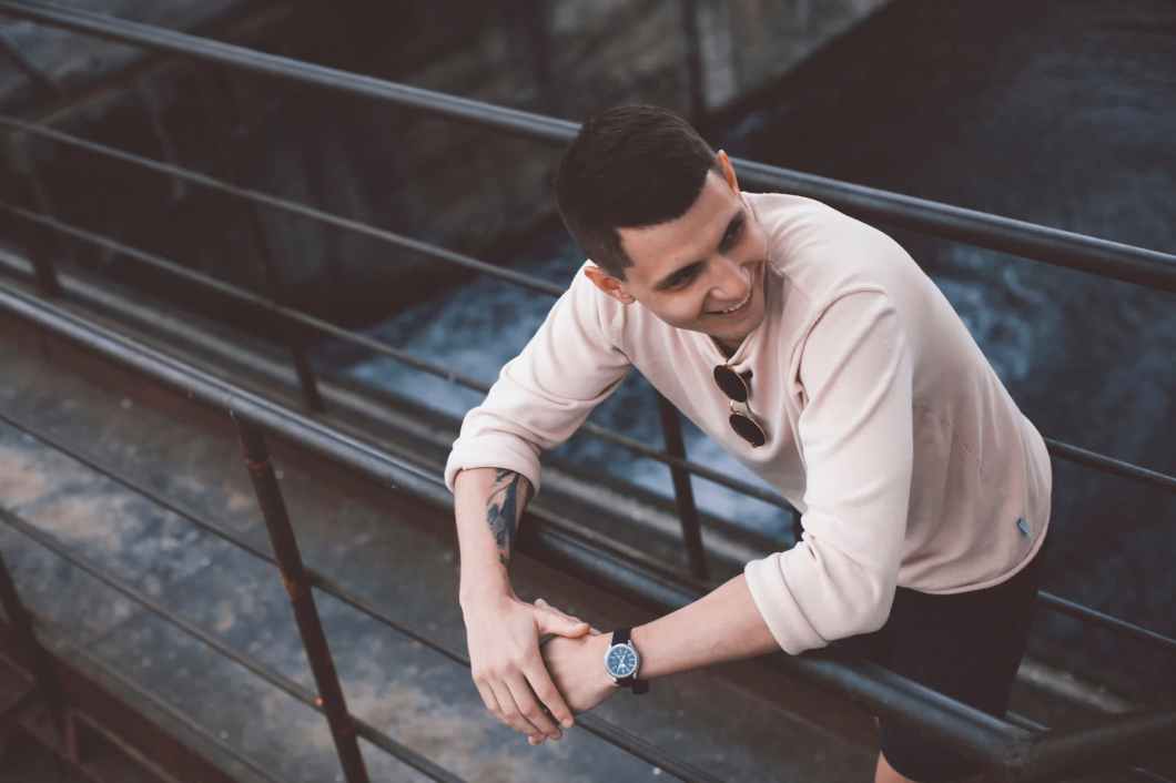man smiling while leaning on railings