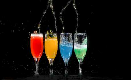 four champagne flutes with assorted color liquids
